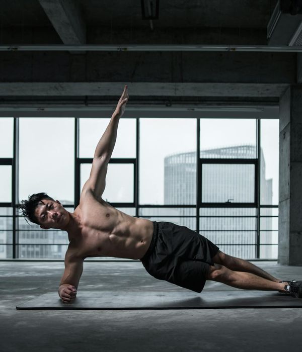 Athletic man performing stability exercises in a modern dark gym environment